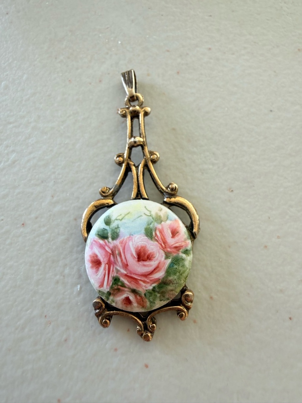 Vintage hand painted porcelain pendant.  Features Roses ornate gold-tone frame